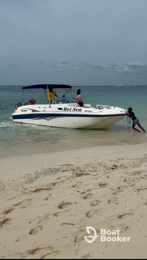 A family enjoys a day at the beach as they approach the boat 'Bet Sea' — a perfect setting for fun in the sun and water activities.