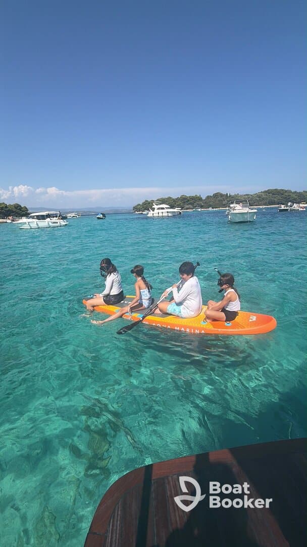 A group of children paddleboards in crystal-clear waters, enjoying a fun day on the water — perfect for family adventures and water sports.