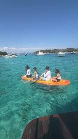 A group of children paddleboards in crystal-clear waters, enjoying a fun day on the water — perfect for family adventures and water sports.