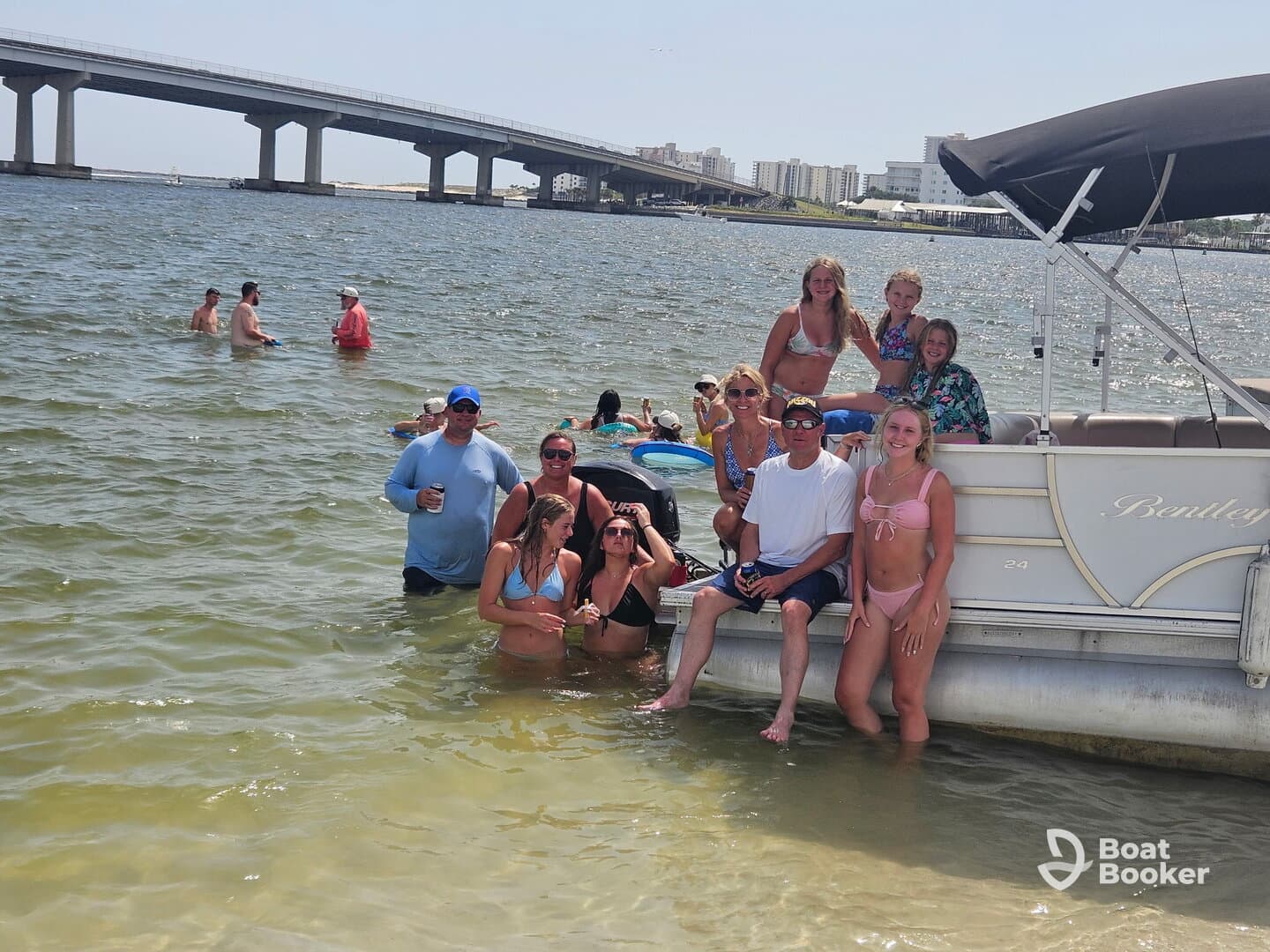 A lively group enjoys a fun day at the sandbar, swimming and relaxing around a pontoon boat, creating unforgettable summer memories.