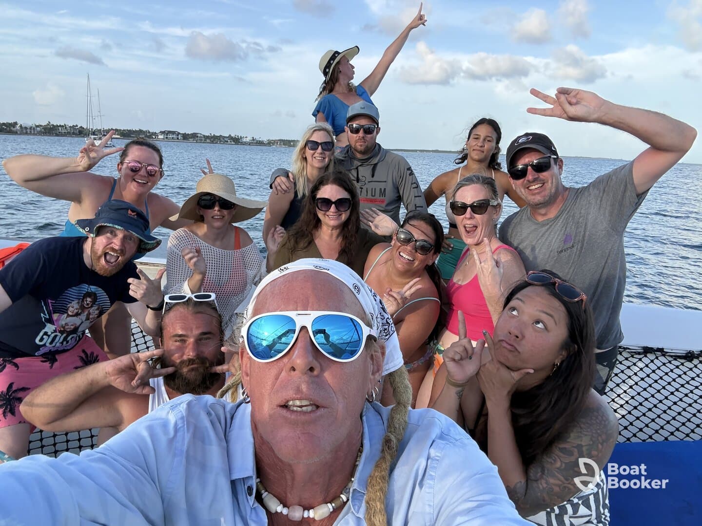A lively group of friends poses for a fun selfie on a boat, capturing the joy of their celebration on the water.