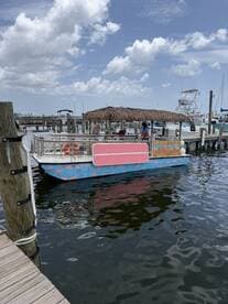 A colorful tiki boat docked at the marina, surrounded by clear waters and a picturesque sky — perfect for fun outings and group adventures.