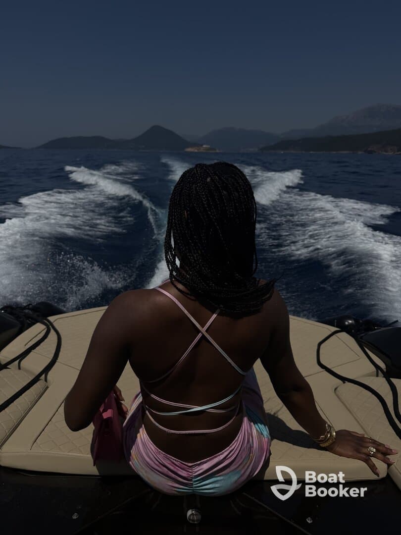 A woman enjoys the view from the back of a boat, surrounded by stunning scenery and the open water — a perfect moment for relaxation and adventure.
