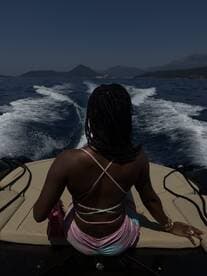 A woman enjoys the view from the back of a boat, surrounded by stunning scenery and the open water — a perfect moment for relaxation and adventure.