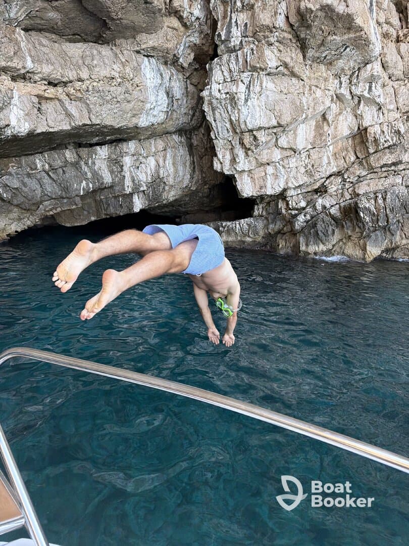 A child jumps into the crystal-clear waters near a rocky coast, showcasing a fun and adventurous moment perfect for family outings and snorkeling adventures.