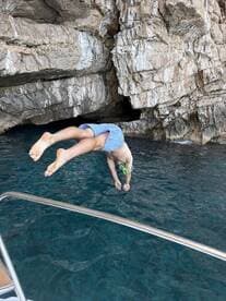 A child jumps into the crystal-clear waters near a rocky coast, showcasing a fun and adventurous moment perfect for family outings and snorkeling adventures.