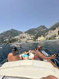 A lively group enjoys a day on the water, capturing memories against the stunning backdrop of Positano's colorful coastline.