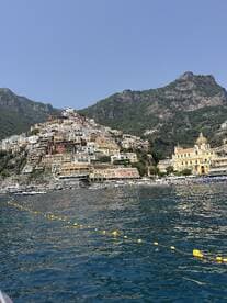 A stunning view of the picturesque coastal town of Positano, nestled against the mountains, showcasing vibrant buildings and a serene harbor — a perfect destination for boat tours along the Amalfi Coast.