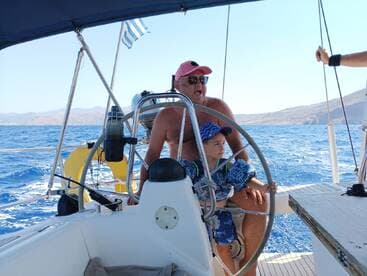 A father and son enjoy a sailing adventure together, with the stunning ocean backdrop highlighting their bonding experience on the water.