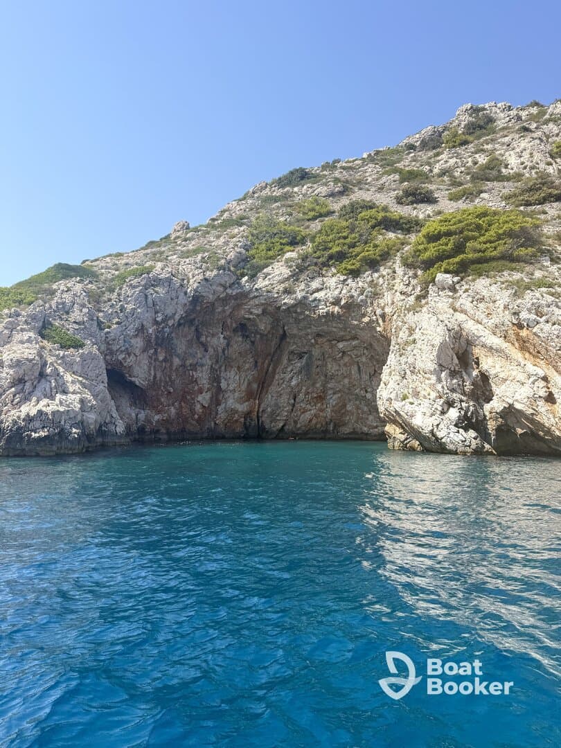 A stunning view of rocky cliffs rising above crystal-clear blue waters, showcasing the natural beauty of the coastline — perfect for scenic boat tours and exploration.