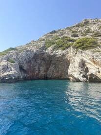 A stunning view of rocky cliffs rising above crystal-clear blue waters, showcasing the natural beauty of the coastline — perfect for scenic boat tours and exploration.