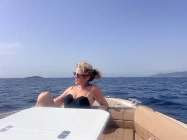 A woman relaxes on the deck of a boat, enjoying the sunny ocean views — a perfect moment for leisure on the water.