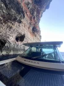 A scenic view of a boat navigating through a cave, showcasing the stunning rock formations and water reflections — perfect for adventure seekers exploring coastal wonders.