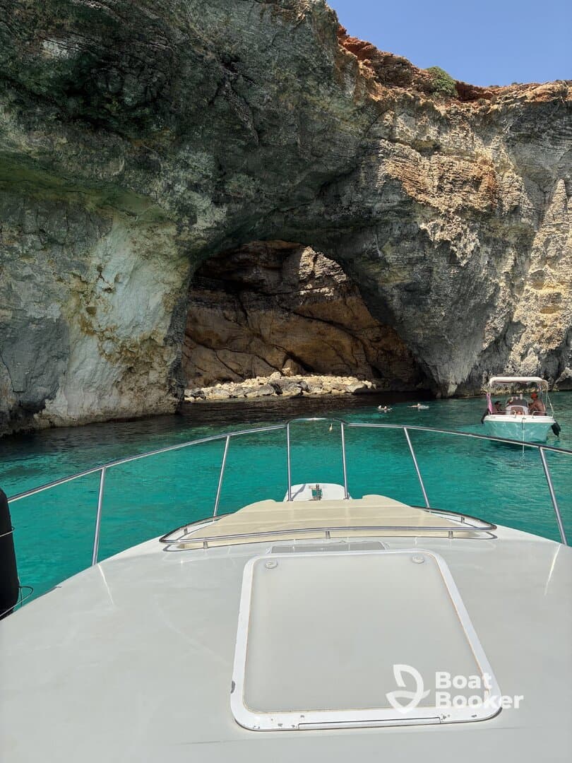 A stunning view of a boat approaching a natural cave, surrounded by crystal-clear turquoise waters — perfect for exploring coastal wonders.