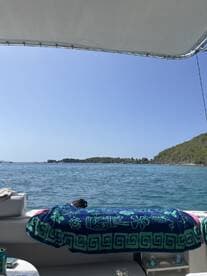 A cozy interior view of a boat featuring a colorful towel draped over the seating area, perfect for relaxing while enjoying the scenic waterfront.