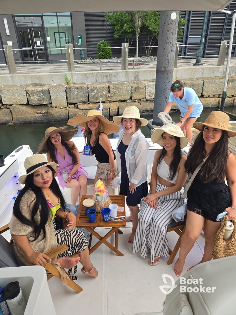 A lively group of friends enjoys a fun day on the boat, showcasing their stylish hats and drinks — perfect for celebrations and memorable outings on the water.