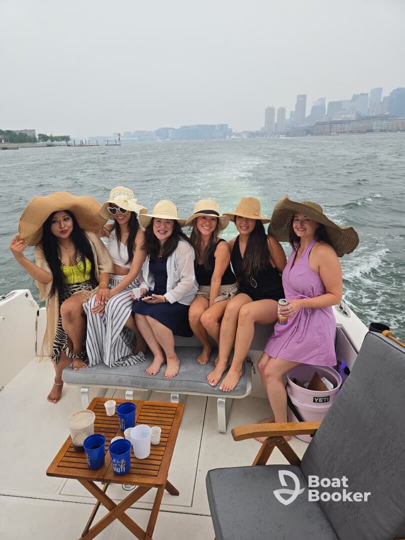 A lively group of friends enjoys a fun day on the water, celebrating together aboard a boat with drinks and laughter, perfect for a bachelorette party or summer outing.