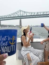 Two friends enjoy drinks on a boat while celebrating with the iconic bridge in the background — a perfect moment for a fun day on the water.