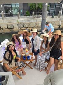A lively group of friends enjoys a fun day on the boat, showcasing their stylish hats and drinks — perfect for celebrations and memorable outings on the water.