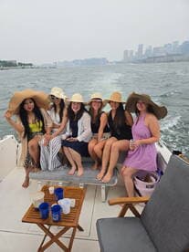 A lively group of friends enjoys a fun day on the water, celebrating together aboard a boat with drinks and laughter, perfect for a bachelorette party or summer outing.