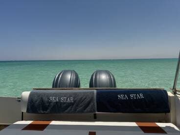 A view of the interior seating area on a boat named 'Sea Star', showcasing the serene turquoise waters in the background, perfect for relaxing on a sunny day.