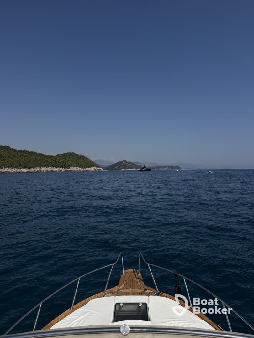 A stunning view from the front of a boat cruising through calm waters, showcasing the serene landscape and clear blue skies.