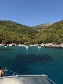 A scenic view of a tranquil bay with multiple boats anchored, showcasing the beauty of nature and a perfect spot for swimming and relaxation.
