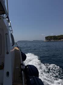 A side view of a boat cruising through calm waters, showcasing the vessel's sleek design and the beautiful coastal scenery in the background.