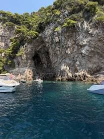 A vibrant scene showcasing boats anchored near a stunning rocky coastline, with guests enjoying the water — perfect for a day of exploration and relaxation.