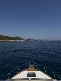 A stunning view from the front of a boat cruising through calm waters, showcasing the serene landscape and clear blue skies.