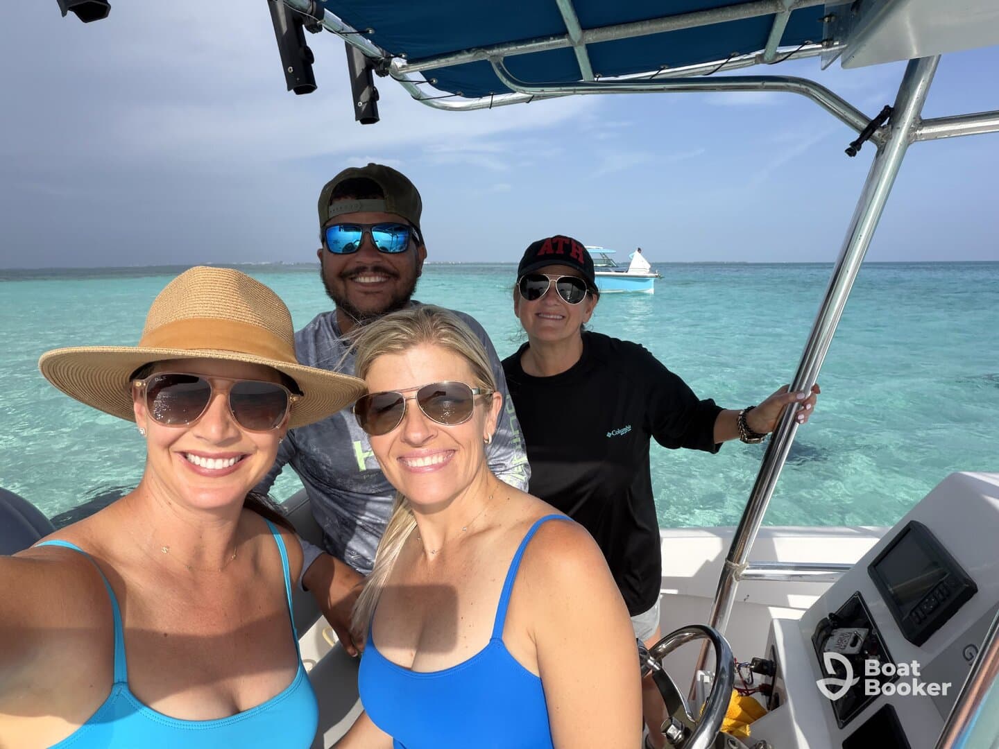 A cheerful group of friends enjoys a day on the water, capturing memories aboard their boat in crystal-clear waters.