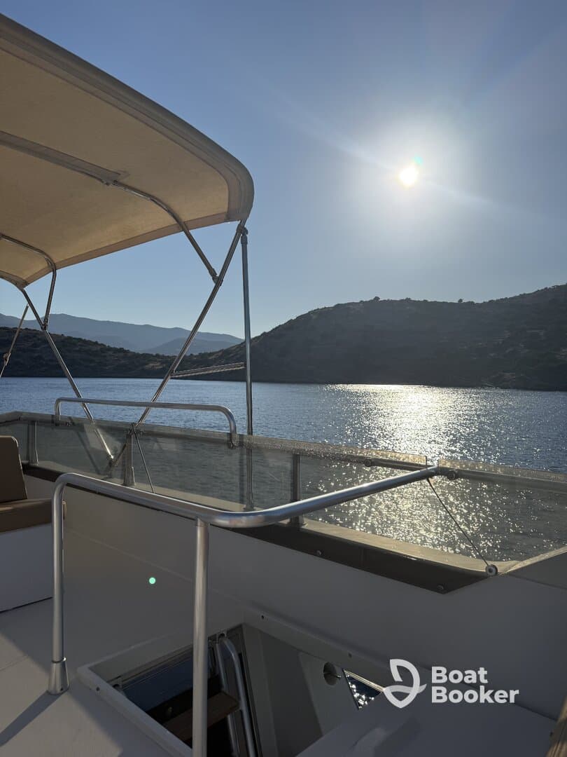 A serene view of a boat's deck under bright sunlight, showcasing the tranquil waters and surrounding hills — perfect for a peaceful day on the water.