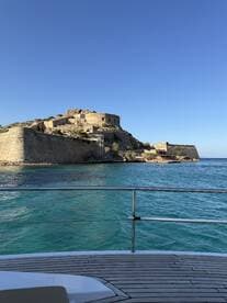 A stunning view of a historic fortress overlooking turquoise waters, captured from the deck of a boat — a perfect backdrop for exploring coastal landmarks.