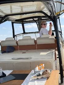 A cheerful guest enjoys the helm of a stylish boat, showcasing the comfortable seating and amenities onboard, perfect for a day of relaxation on the water.