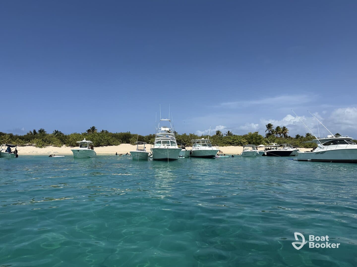 A vibrant scene at a sandbar with multiple boats anchored, showcasing a perfect day for swimming and relaxation on the beach.