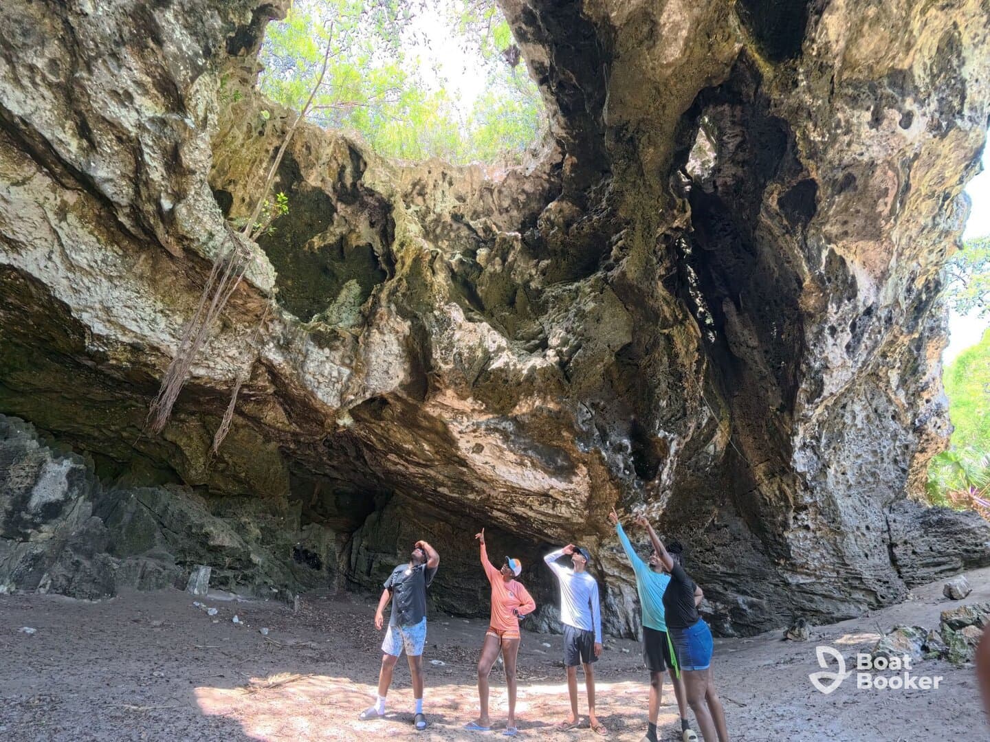 A group of friends explores a stunning cave, pointing at the unique rock formations above — a perfect adventure in nature.