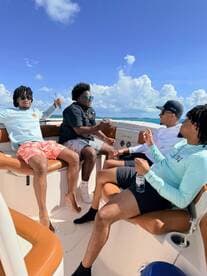 A group of friends enjoys a lively moment aboard a boat, sharing drinks and laughter under a bright blue sky — perfect for a day of fun on the water.