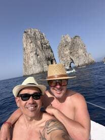 Two friends pose for a selfie in front of the iconic rock formations at Cabo San Lucas, capturing a memorable moment during their boating adventure.