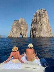 Two friends relax on the bow of a boat, enjoying the stunning view of the iconic rock formations of Capri — a perfect moment for sightseeing and adventure on the water.