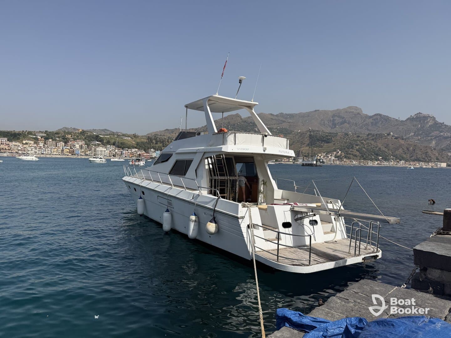 A sleek yacht docked in a picturesque harbor, showcasing its elegant design against a backdrop of coastal scenery.