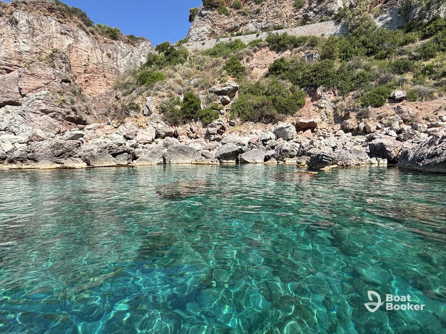 A stunning view of crystal-clear waters reflecting the rocky coastline, perfect for exploring hidden coves and enjoying nature's beauty.