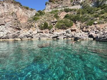 A stunning view of crystal-clear waters reflecting the rocky coastline, perfect for exploring hidden coves and enjoying nature's beauty.