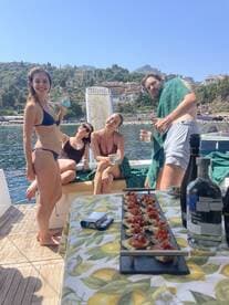 A lively group enjoys drinks and delicious snacks aboard a boat, capturing the essence of a perfect summer day on the water.