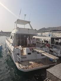 A group of friends poses on the deck of a boat docked at the marina, showcasing a perfect day out on the water.