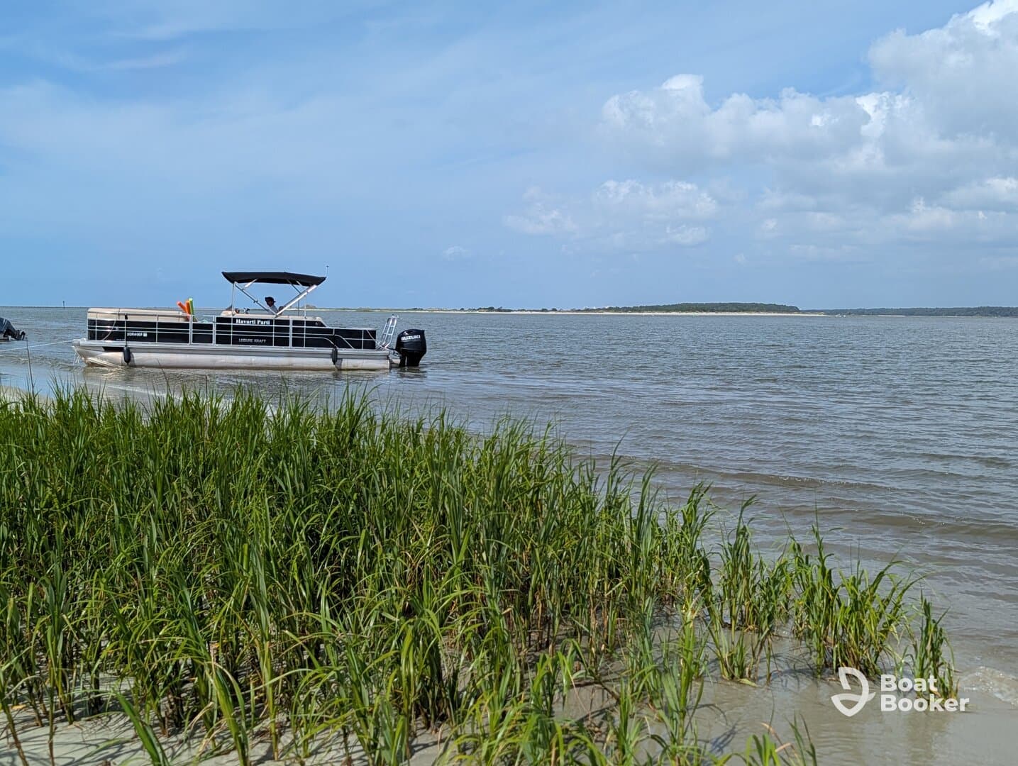 A pontoon boat is docked near the shore, surrounded by lush greenery and calm waters, perfect for leisurely outings on the water.