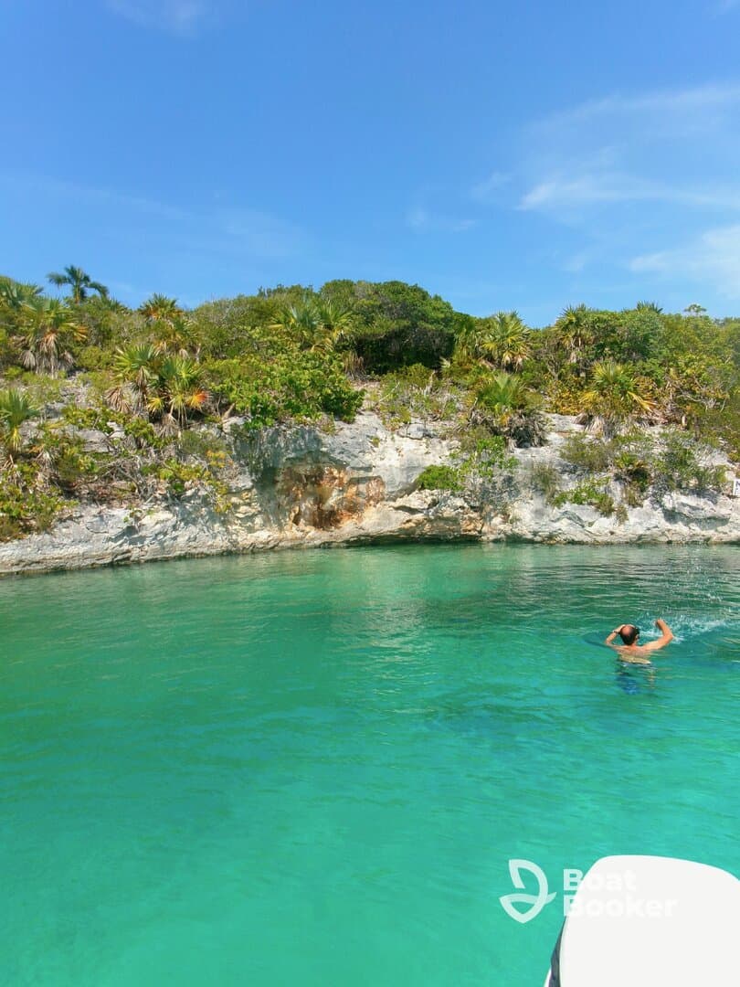 A swimmer enjoys the crystal-clear waters near a lush coastline, showcasing the beauty of a tropical getaway.