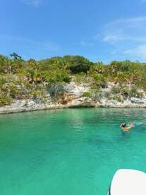 A swimmer enjoys the crystal-clear waters near a lush coastline, showcasing the beauty of a tropical getaway.