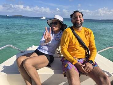 A joyful couple enjoys their time on a boat, capturing the essence of fun and relaxation on the water with a stunning ocean backdrop.