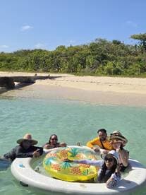 A lively group enjoys a fun day at the beach, relaxing on an inflatable float in the clear waters, perfect for creating unforgettable memories under the sun.