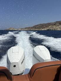 A dynamic view from the back of a speedboat, showcasing powerful Mercury engines as it cuts through the waves, perfect for thrilling water adventures.
